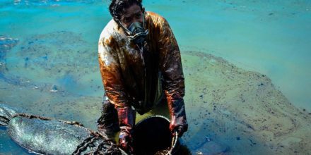 A man scoops leaked oil from the vessel MV Wakashio
